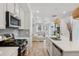 Well-lit kitchen with white cabinets, stainless steel appliances and a kitchen island overlooking living room at 17039 E Exposition Dr, Aurora, CO 80017