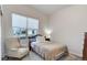 A bedroom with neutral carpet and an armchair facing a window at 12668 Ulster St, Thornton, CO 80602