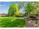 Beautiful backyard featuring a lush lawn, mature trees, and landscaped garden beds at 3720 S Willow Cir, Denver, CO 80237