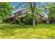 Beautifully landscaped front yard with mature trees surrounding a brick home at 3720 S Willow Cir, Denver, CO 80237