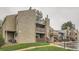 A multi-story apartment building with a textured exterior and wooden balconies and stairs is set in a green space at 5300 E Cherry Creek South Dr # 217, Denver, CO 80246