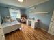 Bright bedroom featuring hardwood floors, a cozy bed, a small desk, and blue accent walls at 12196 Helena St, Commerce City, CO 80603