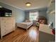 Well-lit bedroom with hardwood floors, a white dresser, and a cozy chair at 12196 Helena St, Commerce City, CO 80603