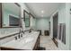 Light-filled bathroom with marble countertops, double sinks, updated fixtures, and natural wood cabinets at 4643 S Vrain St, Denver, CO 80236
