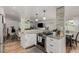 Open concept kitchen view to living area, white cabinets, stainless steel appliances, and stone accents at 4643 S Vrain St, Denver, CO 80236