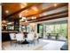 Open dining room with wood-beam ceiling, modern light fixture, and sliding doors to a deck with outdoor dining at 3355 E Eastman Ave, Denver, CO 80210