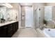 Bathroom showcasing a double sink vanity with dark wood cabinets, tile floors and a glass shower at 23742 E Calhoun Ave, Aurora, CO 80016
