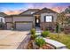Beautiful home with stone accents, a three-car garage, and manicured landscaping against a colorful sky at 23742 E Calhoun Ave, Aurora, CO 80016