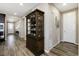 Hallway featuring dark wood floors, a glass front cabinet, and natural light from the nearby front door at 23742 E Calhoun Ave, Aurora, CO 80016