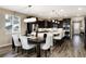 Modern kitchen featuring dark cabinets, stainless steel appliances, large island, and nearby dining area with seating at 23742 E Calhoun Ave, Aurora, CO 80016