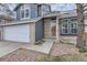 Detailed view of a home's exterior with blue siding, brick accents, a two-car garage, and a walkway at 9902 Independence St, Broomfield, CO 80021