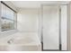 Bathroom features a soaking tub with shower combo, window, and glass shower door at 3745 Balderas St, Brighton, CO 80601