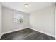 Simple bedroom with dark wood floors, a window overlooking the yard, and neutral paint at 3745 Balderas St, Brighton, CO 80601