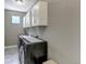 Modern laundry room with gray walls, tiled floors, white cabinets, and sleek black appliances at 11494 Colony Loop, Parker, CO 80138
