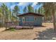 Attractive blue cabin with deck and steps, surrounded by trees at 28 Deer Rd, Evergreen, CO 80439