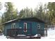 Quaint blue cabin with a deck, nestled in a snowy forest setting at 28 Deer Rd, Evergreen, CO 80439