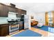Modern kitchen with stainless steel appliances and dark wood cabinets, open to a cozy living room space at 3059 Curtis St, Denver, CO 80205