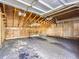 Unfinished garage with exposed wooden beams, paneled walls, and a concrete floor in need of repair at 11612 E Cornell Cir, Aurora, CO 80014