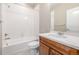Bathroom features a shower/tub combo with white tiled walls, a toilet, vanity with a sink and wooden cabinets at 12953 Bridge View Ln, Parker, CO 80134