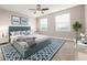 Bright primary bedroom with large windows, ceiling fan, soft carpet, accent rug and comfortable queen-size bed at 12953 Bridge View Ln, Parker, CO 80134