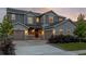 Inviting gray two-story home boasts a three-car garage, manicured landscaping, and a welcoming front porch at 12953 Bridge View Ln, Parker, CO 80134