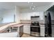 Functional kitchen featuring modern stainless steel appliances, white cabinetry, and bar seating at 7414 S Alkire St # 101, Littleton, CO 80127