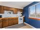 Kitchen with dark wood cabinets, blue wall, and a window with blinds at 902 Pacific Pl, Fort Lupton, CO 80621
