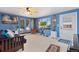 Bright living room featuring surfboards, blue walls, large window, and piano at 902 Pacific Pl, Fort Lupton, CO 80621