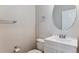 A half bathroom featuring a white vanity, toilet, and a round mirror at 6000 W Floyd Ave # 116, Denver, CO 80227
