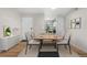 Bright dining area featuring wood-look floors, a modern table setting, and access to the kitchen at 3656 S Depew St # 102, Denver, CO 80235