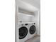 A bright, modern laundry room with front load washer and dryer, shelving, and tile floors at 3656 S Depew St # 102, Denver, CO 80235