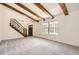 Inviting living room features exposed wood beams, plush carpet, and a staircase with wrought iron railings at 12454 Antelope Trl, Parker, CO 80138
