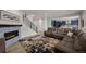 Open-concept living room with stone fireplace, plush sectional sofa and open access to the kitchen at 6220 Waterman Way, Frederick, CO 80516