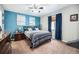 Comfortable bedroom with a blue accent wall, neutral carpet, and a large window with blue curtains at 1030 S Fulton Ave, Fort Lupton, CO 80621