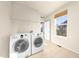 Bright laundry room with white washer and dryer and tile floors and a window for natural light at 1027 Koss St, Erie, CO 80516