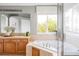 Bright bathroom features a soaking tub under a window and double vanity sinks at 7700 Bison Ct, Littleton, CO 80125
