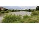 Community pond surrounded by lush greenery and neighborhood homes in the background, promoting a serene environment at 7700 Bison Ct, Littleton, CO 80125