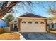 Beige two-car garage door with decorative windows and brick accents on a charming one-story home with a well-maintained driveway at 11586 Chase Way, Westminster, CO 80020