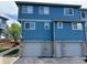 Close-up of townhome garages and entryways featuring blue siding and stone veneer at 12036 Monaco St, Brighton, CO 80602