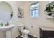 Stylish half bathroom with pedestal sink, round mirror and natural light at 9466 Quintero St, Commerce City, CO 80022