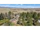 High-angle aerial view captures the home's location amidst trees, with a field and distant mountains at 7904 Hill Crest Dr, Louviers, CO 80131