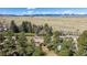 Expansive aerial shot showcasing the property, mature trees, and a backdrop of mountains in the distance at 7904 Hill Crest Dr, Louviers, CO 80131