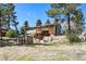 Backyard view of a two-story house with a wooden deck, shed, and surrounding greenery under a clear sky at 7904 Hill Crest Dr, Louviers, CO 80131