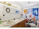Bright bathroom features a double sink vanity with a decorative mirror and a shower-tub combination with a floral curtain at 7904 Hill Crest Dr, Louviers, CO 80131