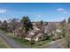 Aerial view of charming yellow home with inviting front porch, surrounded by mature trees and a green lawn at 7835 Valley View St, Louviers, CO 80131