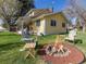 Charming yellow home with a fire pit surrounded by Adirondack chairs for outdoor gatherings at 7835 Valley View St, Louviers, CO 80131