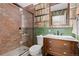 Unique bathroom with brick shower, glass door, and distinctive bookshelf wallpaper at 7835 Valley View St, Louviers, CO 80131