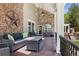 This covered porch showcases outdoor seating, a brick fireplace, and a beautiful exterior with mature trees at 2 University Ln, Greenwood Village, CO 80121