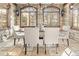 Dining room features stone walls, beamed ceilings, large windows, and modern lighting at 2 University Ln, Greenwood Village, CO 80121