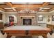Elegant game room with pool table, stone fireplace, and custom lighting with wood beam ceiling at 2 University Ln, Greenwood Village, CO 80121